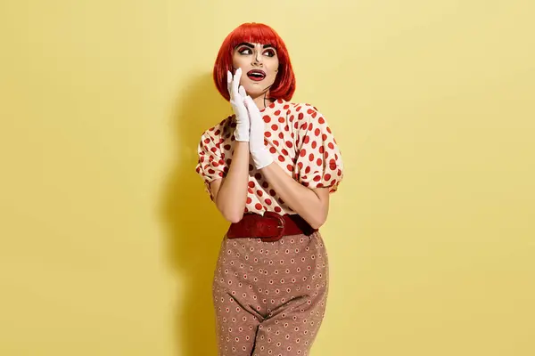A redhead woman with pop art makeup wears a polka dot shirt and white gloves on a yellow background. — Stock Photo