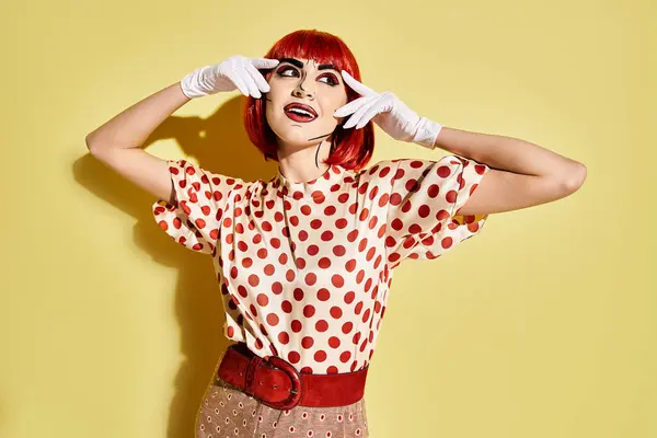 A pretty redhead woman in a polka dot top stands out against a yellow background, her pop art makeup adding a comic character vibe. — Stock Photo