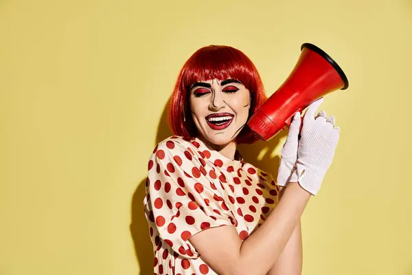 Eine feurige Frau mit Pop-Art-Make-up hält ein rotes Megafon vor einem leuchtend gelben Hintergrund. — Stockfoto