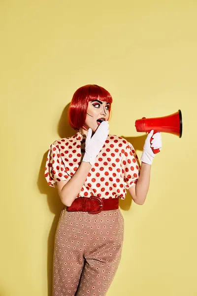 Uma mulher ruiva feroz detém um megafone vermelho e branco, exalando confiança com sua maquiagem pop art e blusa de bolinhas. — Fotografia de Stock