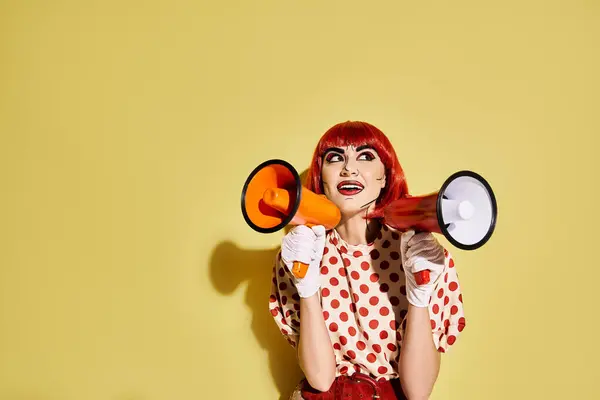 Eine auffallend rothaarige Frau mit Pop-Art-Make-up hält ein Megafon vor einem leuchtend gelben Hintergrund. — Stockfoto