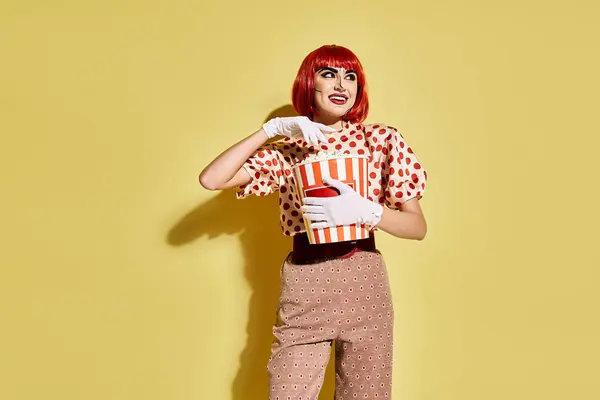 Woman with red hair holding box of popcorn on yellow background in comic-inspired pop art style. — Stock Photo