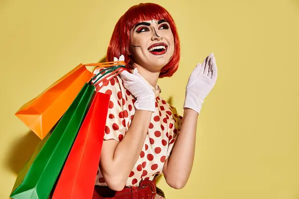 Uma mulher ruiva bonita com maquiagem criativa pop art segurando sacos de compras em um fundo amarelo. — Fotografia de Stock