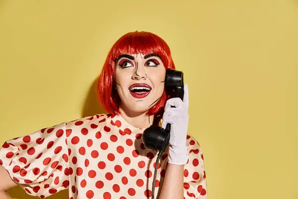 Uma mulher ruiva vibrante em chats de maquiagem inspirados em quadrinhos em um telefone contra um pano de fundo amarelo brilhante. — Fotografia de Stock