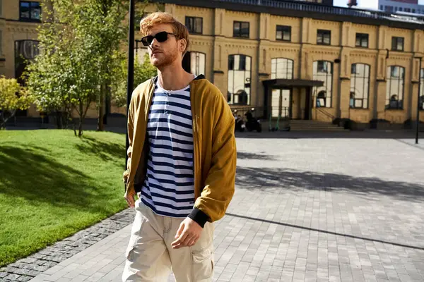 A young red-haired man in debonair attire walking down a city sidewalk. — Stock Photo
