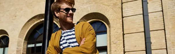 A young man with red hair and a debonair attire standing in front of a building in the city. — Stock Photo