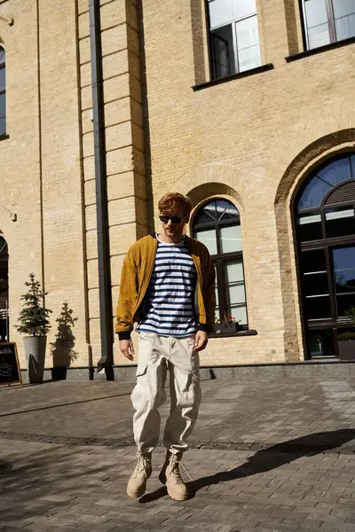Young red-haired man in debonair attire standing gracefully in front of a city building. — Stock Photo