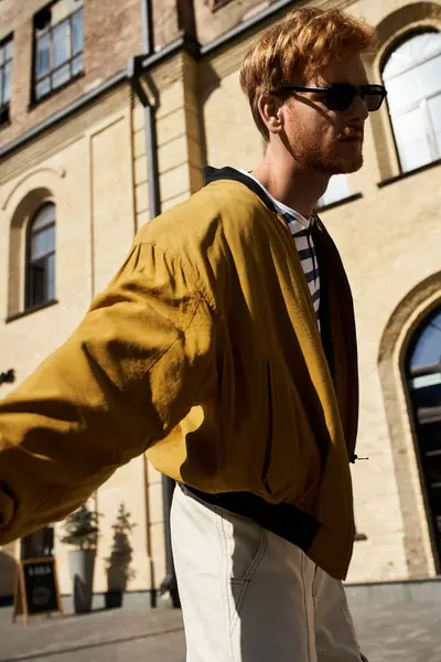 Young man with red hair in yellow jacket and tie walking down city street. — Stock Photo