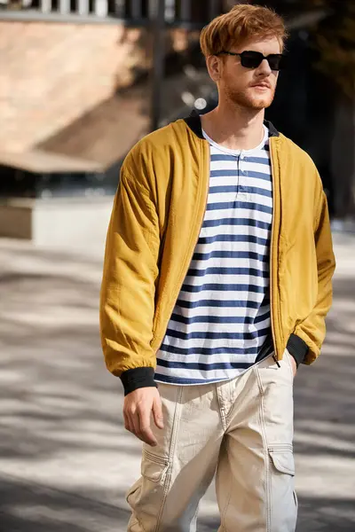 A red-haired man in a stylish yellow jacket strolling down the city street. — Stock Photo