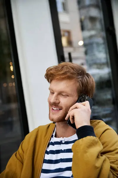 Red-haired man in debonair attire sits outdoors, talking on cell phone. — Stock Photo