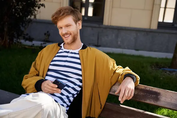 Red-haired man in debonair attire seated on top of wooden bench. — Stock Photo
