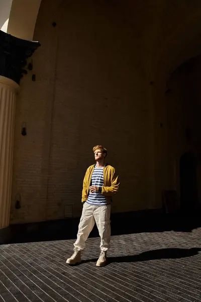 Young red-haired man in debonair attire standing confidently in front of a modern building in the city. — Stock Photo
