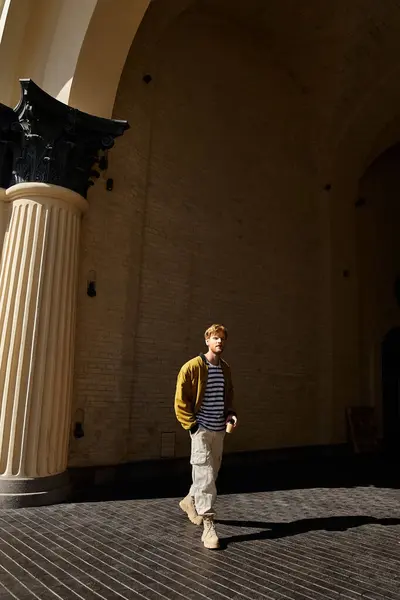 Un joven pelirrojo vestido con el atuendo de debonair se para con confianza frente a un impresionante edificio. - foto de stock