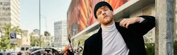 Young red-haired man in debonair attire leaning against a city wall. — Stock Photo