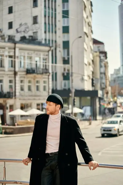 Red-haired man in debonair black coat and hat leaning on rail. — Stock Photo