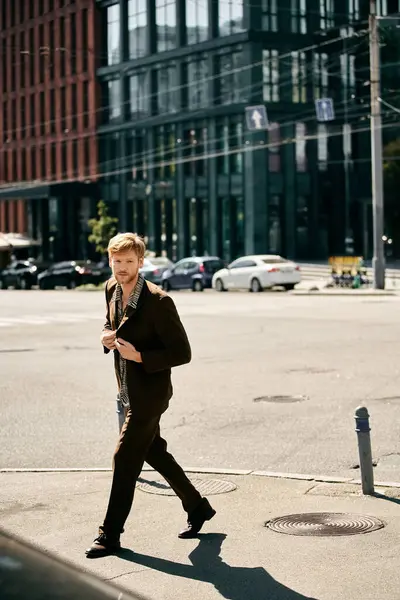 A young red-haired man in debonair attire gracefully walks across a street next to a tall building. — Stock Photo