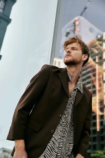 Un hombre de pelo rojo elegante de pie frente a un edificio imponente en la ciudad. — Stock Photo