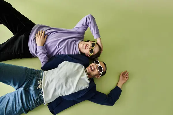 Два стильных человека наслаждаются солнцем, сидя на земле в солнцезащитных очках. — стоковое фото