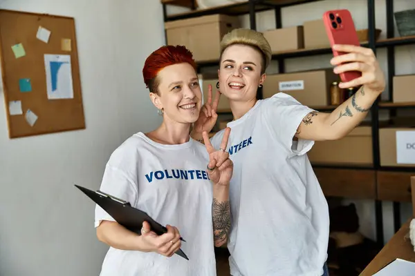 Two young women in volunteer t-shirts stand side by side, embodying teamwork and collaboration in charity work. — Stock Photo