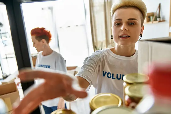 A young woman in a t-shirt in a kitchen setting, part of a lesbian couple volunteering together. — Stock Photo