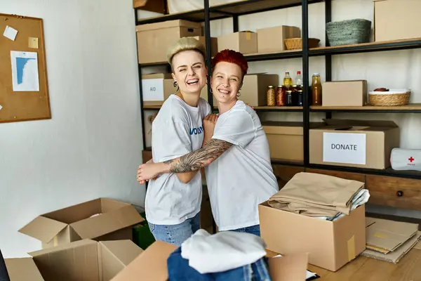 A couple of young women in volunteer t-shirts standing together, actively engaged in charity work. — Stock Photo