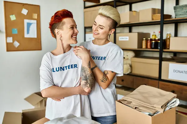 A lesbian couple in volunteer t-shirts work together in charity. — Stock Photo