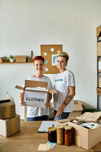 Deux jeunes femmes en t-shirts bénévoles se tiennent côte à côte, unies dans leurs efforts pour faire du travail de charité. — Photo de stock