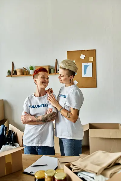 Two women in volunteer t-shirts, partners in charity work, standing side by side. — Stock Photo