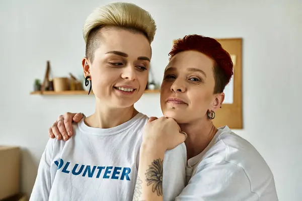 A lesbian couple in volunteer t-shirts standing shoulder to shoulder, engaged in charity work and empowerment efforts. — Stock Photo