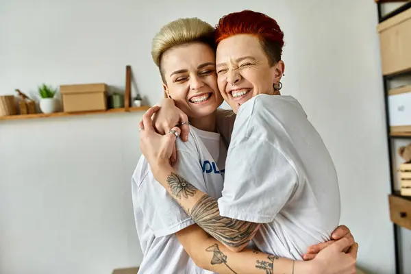 Young women in volunteer t-shirts embrace in a warm hug as they work together for a charitable cause. — стоковое фото