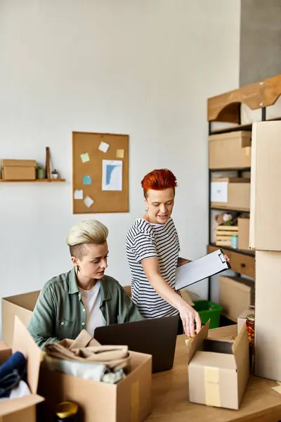 Due giovani donne in maglietta che smistano scatole di donazioni in una stanza piena di beneficenza. — Foto stock