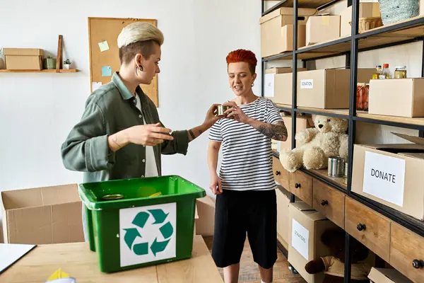 Young lesbian couple, stand in a room filled with boxes while volunteering for a charity. — Stock Photo