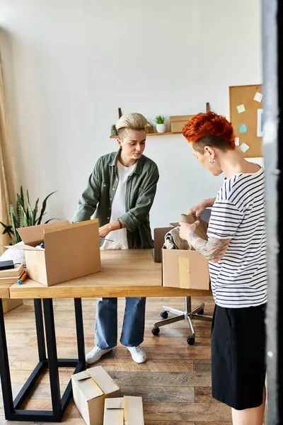 A young lesbian couple working together to organize boxes on a table for a charity project. — Stock Photo