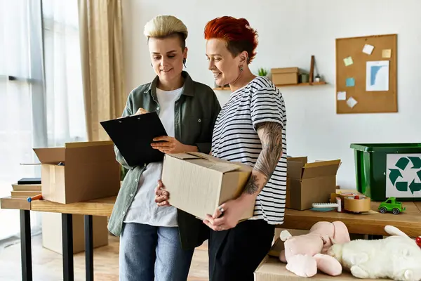 Two young women, a lesbian couple, stand united in a room, dedicated to charitable work. — Stock Photo