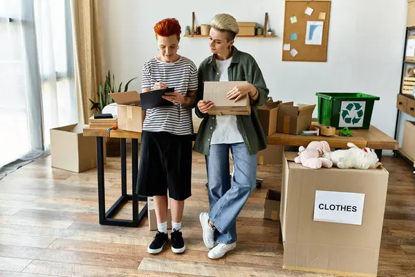 Couple stand in a room filled with boxes, working together on a charity project. — Stock Photo