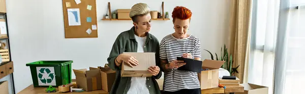 A young lesbian couple collaborating to sort boxes in a charity room. — Stock Photo