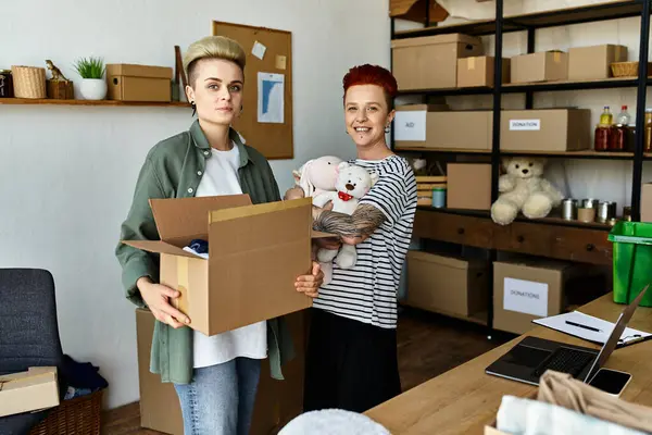 Two women, work together in an office, handling boxes for a charity project. — Stock Photo
