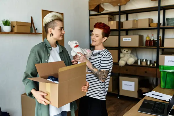 A young woman, part of a lesbian couple, lovingly holds a stuffed animal inside a charity box. — Stock Photo