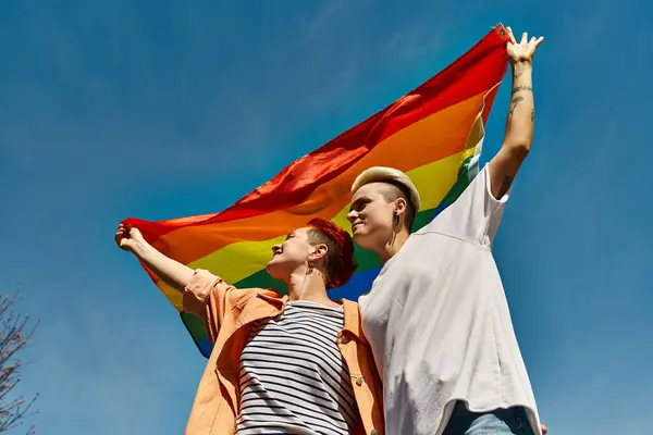 Couple proudly holding a rainbow flag, symbolizing love and pride within the LGBTQ community. — Stock Photo