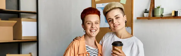 A young lesbian couple stands united in a volunteer center surrounded by boxes, embodying unity and support. — Stock Photo