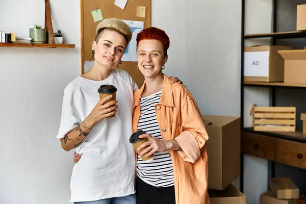 A young lesbian couple stands near charity boxes in a vibrant volunteer center, uniting for a cause. — Stock Photo
