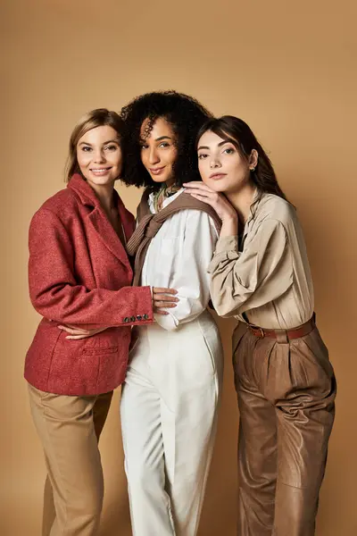Young, beautiful women in stylish attire pose in unity, celebrating diversity in cultures on a beige background. — Stock Photo