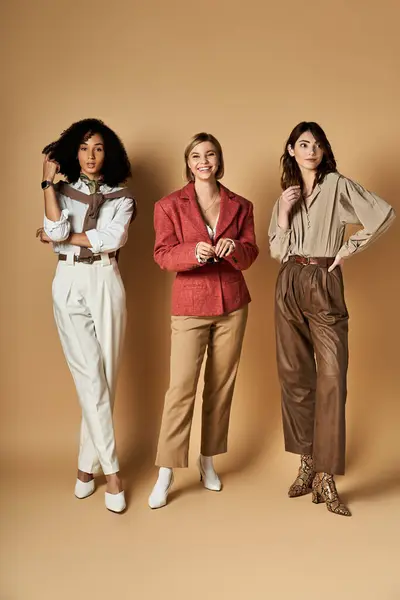 Three multicultural women in chic attire stand together, showcasing friendship and cultural diversity. — Stock Photo