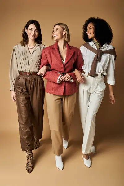 Tre giovani, belle donne in elegante abbigliamento stare fianco a fianco, sorridendo calorosamente in una dimostrazione di amicizia e diversità culturale. — Foto stock
