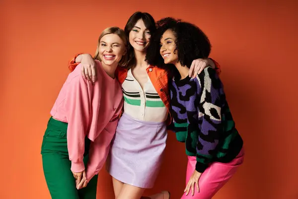 Young, beautiful women in stylish clothes celebrating friendship and cultural diversity on an orange background. — Stock Photo