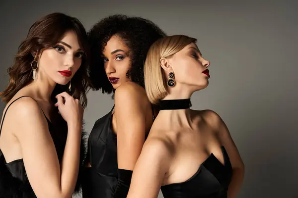 Three beautiful women, from different cultures, exuding grace and sophistication in their black dresses against a grey backdrop. — Stock Photo