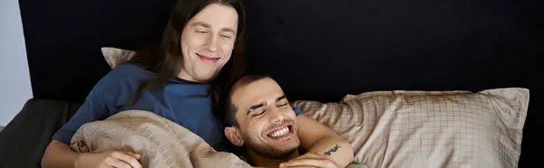 A young gay couple shares a tender moment, laughing and enjoying each others company in their bedroom. — Stock Photo