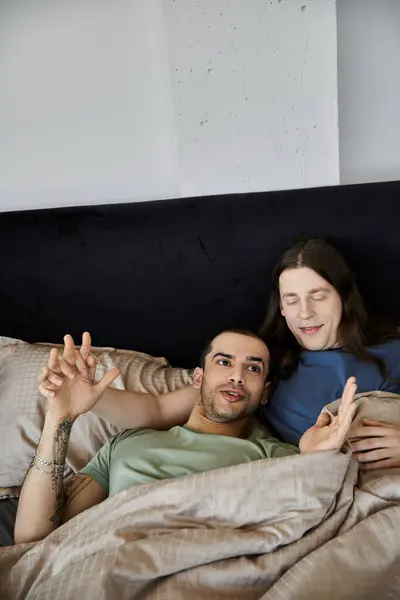 Una giovane coppia gay condivide un momento di intimità e risate mentre si rilassa a letto. — Foto stock