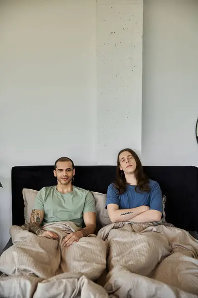 A young gay couple, relaxed and comfortable, share a moment of intimacy in their bedroom. — Stock Photo