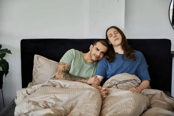 A young gay couple snuggles in bed together, enjoying a moment of intimacy and connection. — Stock Photo